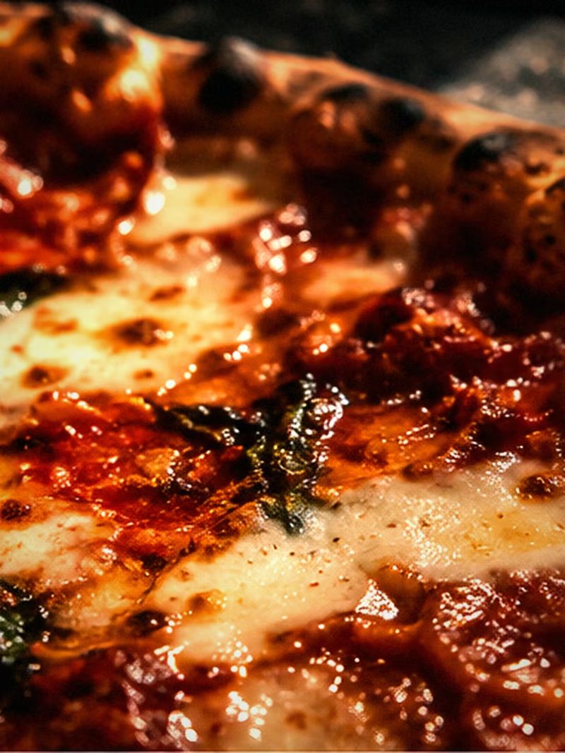 Nahaufnahme einer New-York-Style-Pizza mit geschmolzenem Käse und Basilikum