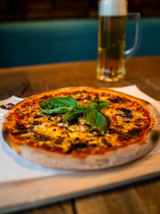 Pizza mit Basilikum und ein Bier