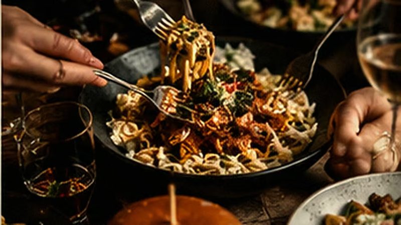 Zwei Gäste essen gemeinsam von mehreren Tellern, Gabeln in Bewegung